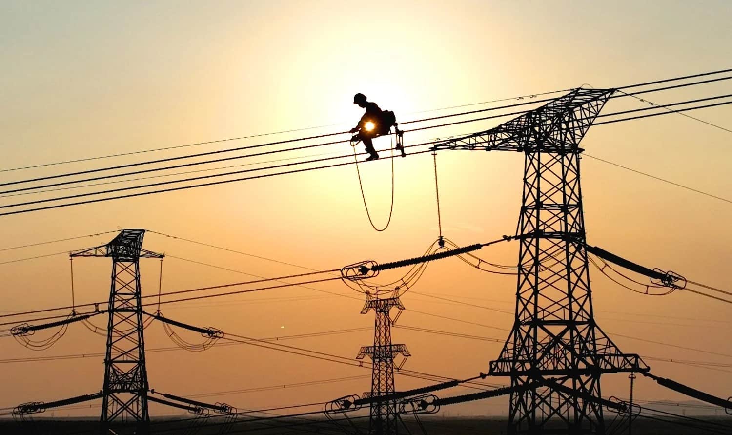 عامل كهرباء يُجري أعمال الصيانة على أسلاك الكهرباء لمشروع خطوط الطاقة ذات الجهد العالي في مدينة ليانيونغانغ الصينية في 28 سبتمبر/ أيلول عام 2022. جينغ يوهي/ في سي جي عن طريق موقع جيتي إميدجيز